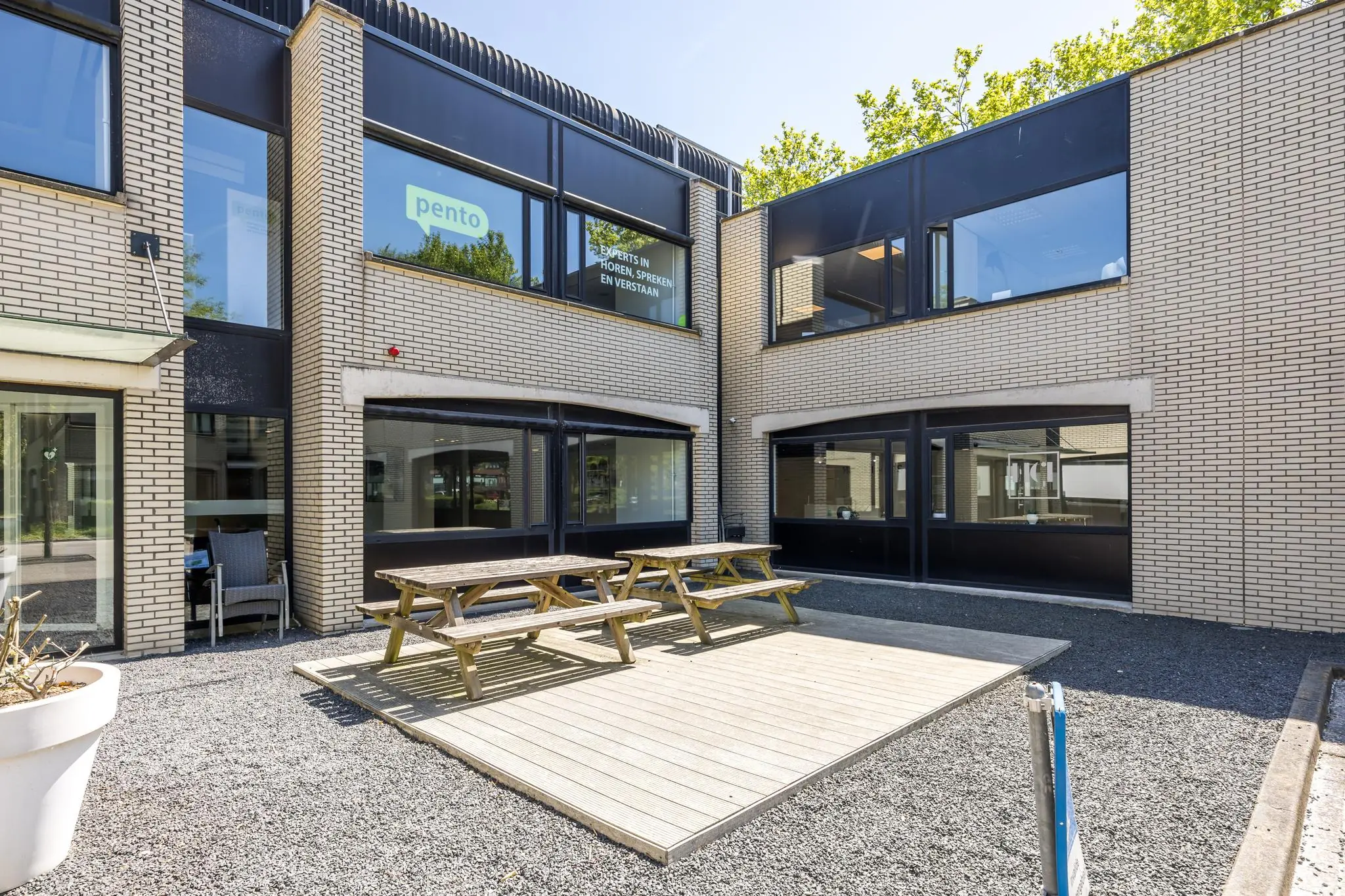 Binnenplaats met houten picknicktafels bij het Pento-gebouw aan de Burgemeester Verderlaan.