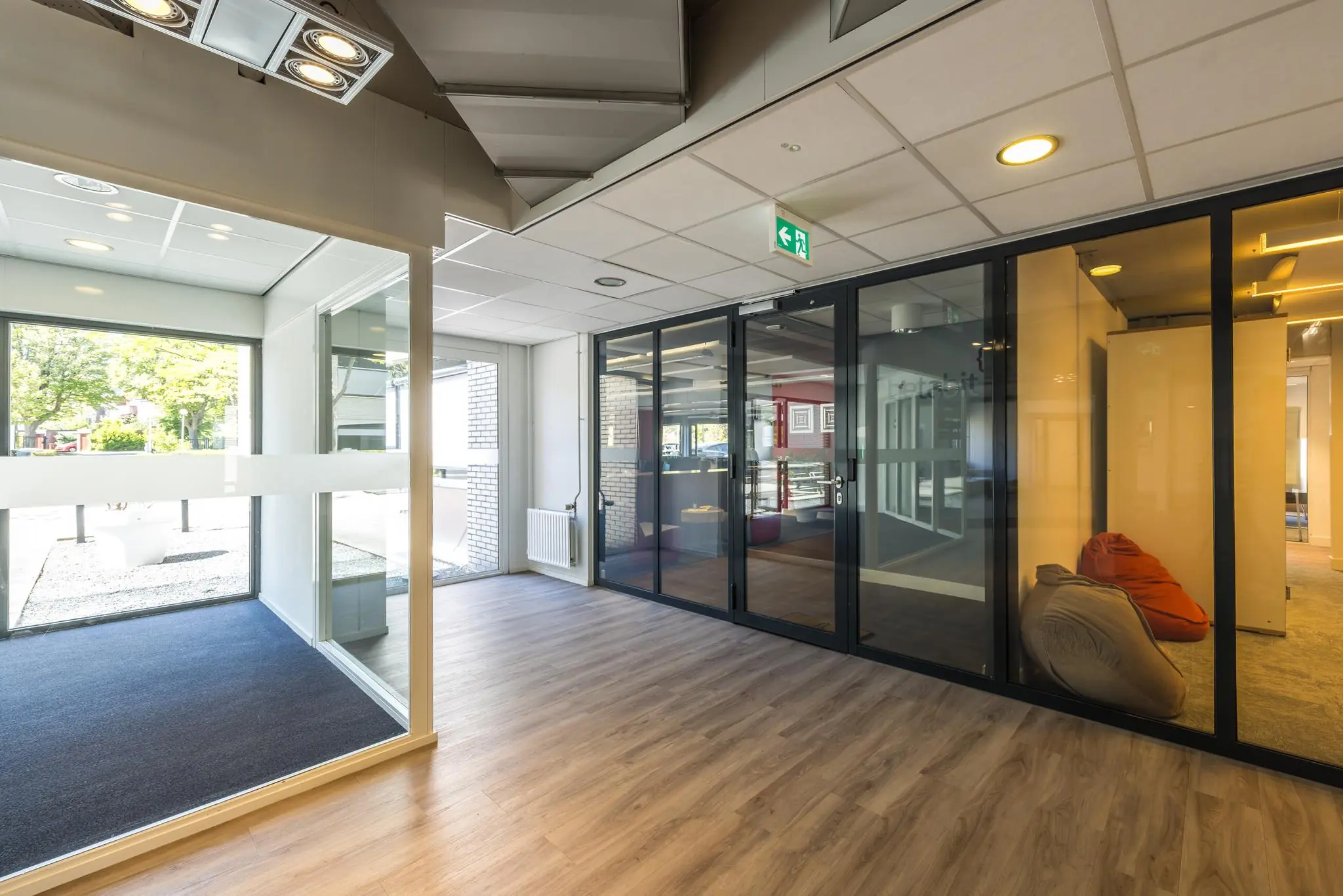 Moderne en lichte kantoorruimte aan de Burgemeester Verderlaan met glazen wanden en zitkussens.