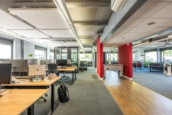 Modern kantoorinterieur aan de Burgemeester Verderlaan met werkplekken, glazen vergaderruimtes en een tafelvoetbaltafel.