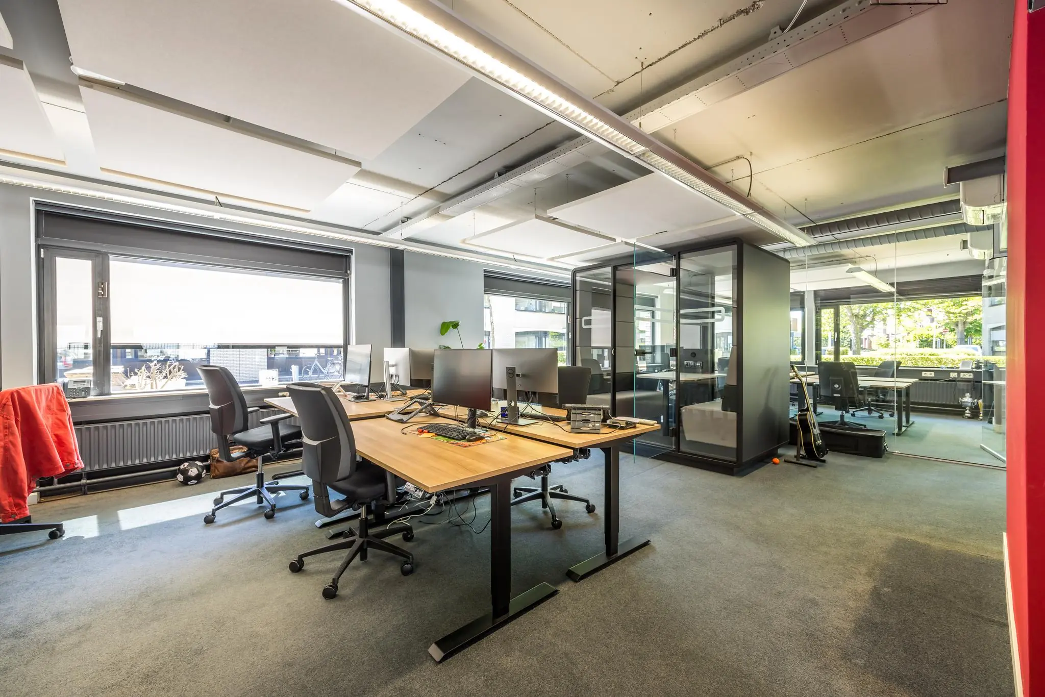 Modern en licht kantoorinterieur aan de Burgemeester Verderlaan met bureaus, computerschermen en glazen vergaderruimte.