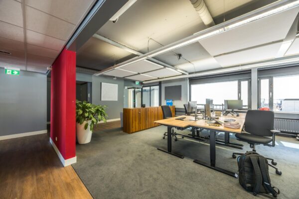 Modern en licht kantoorinterieur aan de Burgemeester Verderlaan met bureaus, bureaustoelen, computers en een houten opbergkast.