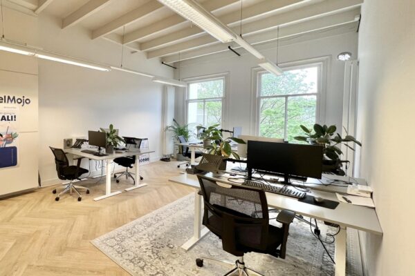 Modern kantoorinterieur aan de Paulus Potterstraat met bureaus, computers en grote ramen met uitzicht op groen.