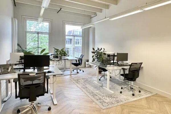 Modern en licht kantoor aan de Paulus Potterstraat met bureaus, bureaustoelen, planten en computers.