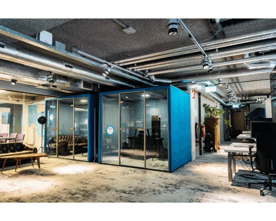 Moderne kantooruimte aan de Wibautstraat met glazen vergaderunits, open werkplekken en industriële inrichting.