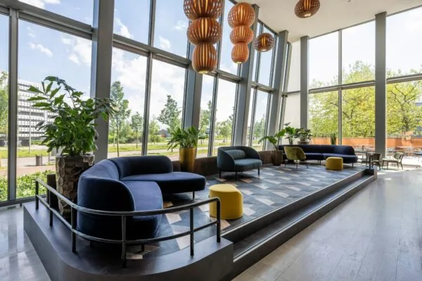 Moderne en lichte wachtruimte aan de David Ricardostraat met grote ramen, designmeubilair en hangende houten lampen.