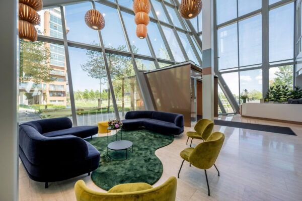 Moderne entreehal aan de David Ricardostraat met grote glazen gevel, designmeubilair en kleurrijke zithoek.