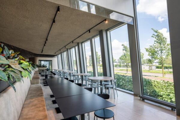 Moderne en lichte zithoek met zwarte en houten tafels langs de grote ramen aan de David Ricardostraat.