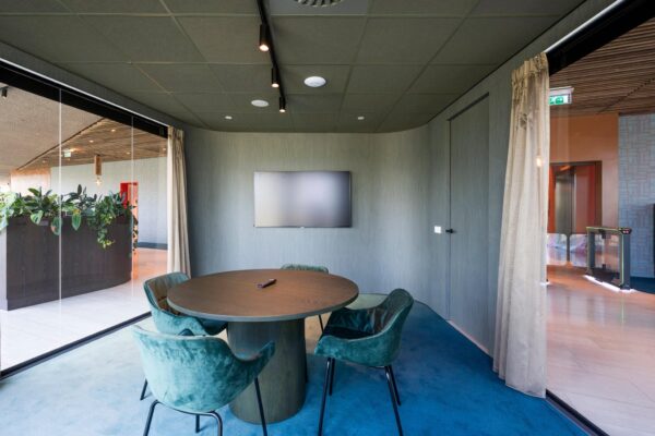 Moderne vergaderruimte aan de David Ricardostraat met ronde tafel, fluwelen stoelen en een flatscreen aan de muur.