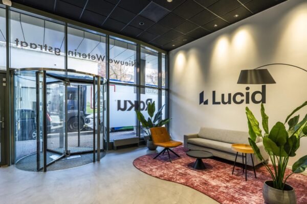 Moderne ontvangsthal van Lucid aan de Vijzelgracht met glazen draaideur, zitgedeelte en interieurplanten.