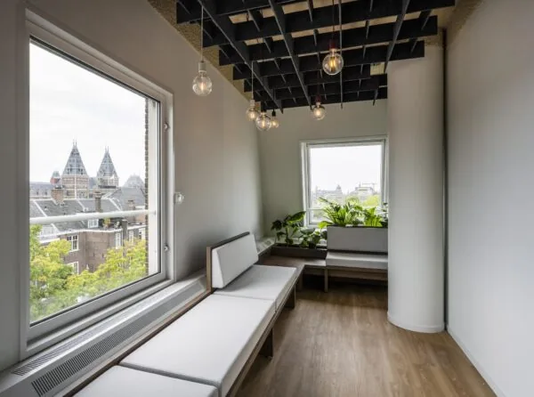 Moderne zitruimte met houten vloer, grote ramen met uitzicht op het Rijksmuseum en groene planten bij Vijzelgracht in Amsterdam.