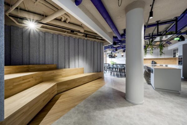 Modern kantoorinterieur aan de Vijzelgracht met houten tribunezitplaatsen, een open keuken en een zithoek met hoge tafels en krukken.