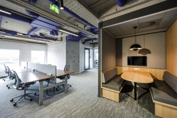 Modern kantoorinterieur aan de Vijzelgracht met flexwerkplekken en een vergaderruimte in nis met tv-scherm.