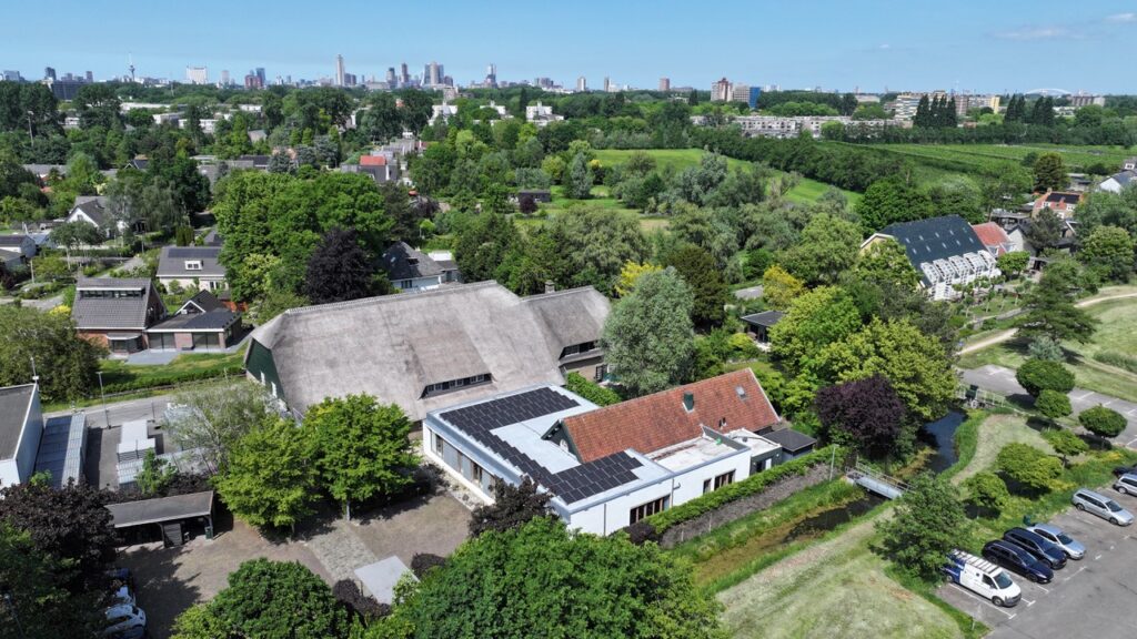 Luchtfoto van de Charloisse Lagedijk in Rotterdam met woningen, groen en zonnepanelen op daken.