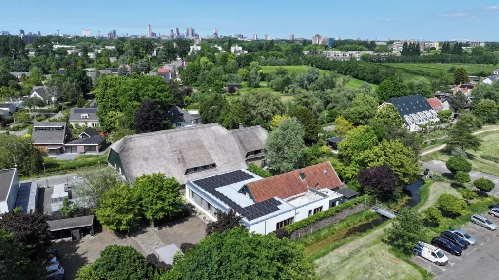 Luchtfoto van de Charloisse Lagedijk in Rotterdam met woningen, groen en zonnepanelen op daken.