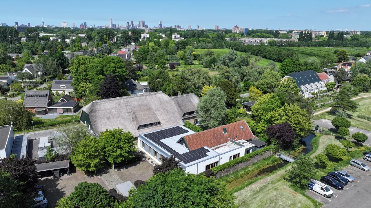 Luchtfoto van de Charloisse Lagedijk in Rotterdam met woningen, groen en zonnepanelen op daken.