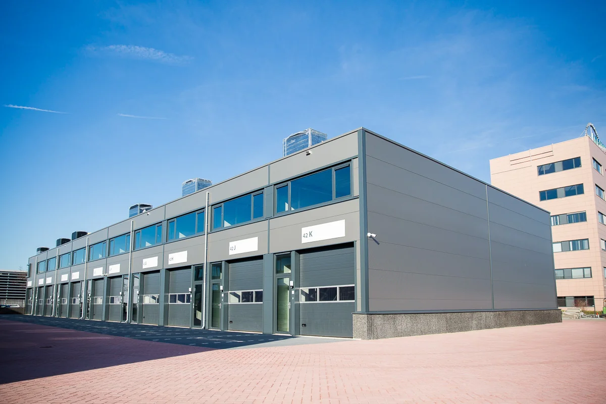 Modern bedrijfsverzamelgebouw aan de Laan van 's-Gravenmade met meerdere bedrijfsunits en overheaddeuren.