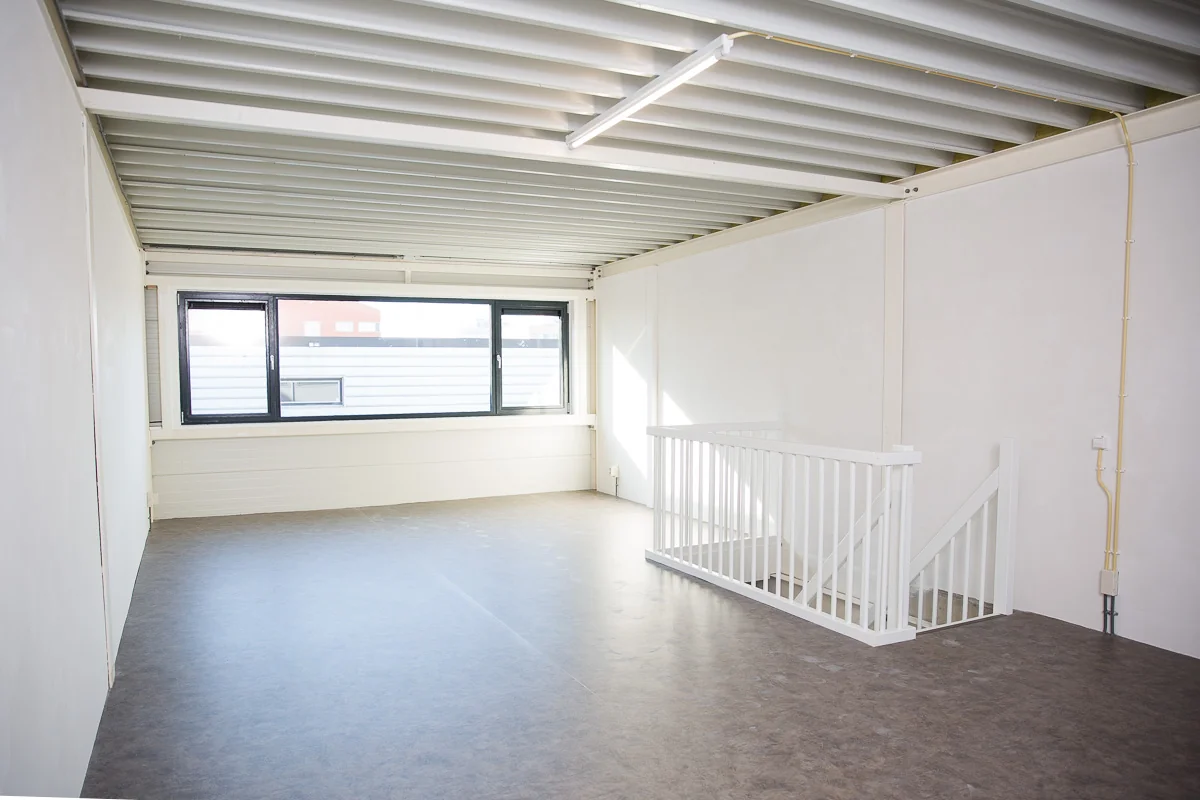 Lichte, lege kantoorruimte aan de Laan van S'‐Gravenmade met grote ramen en een witte trap naar beneden.
