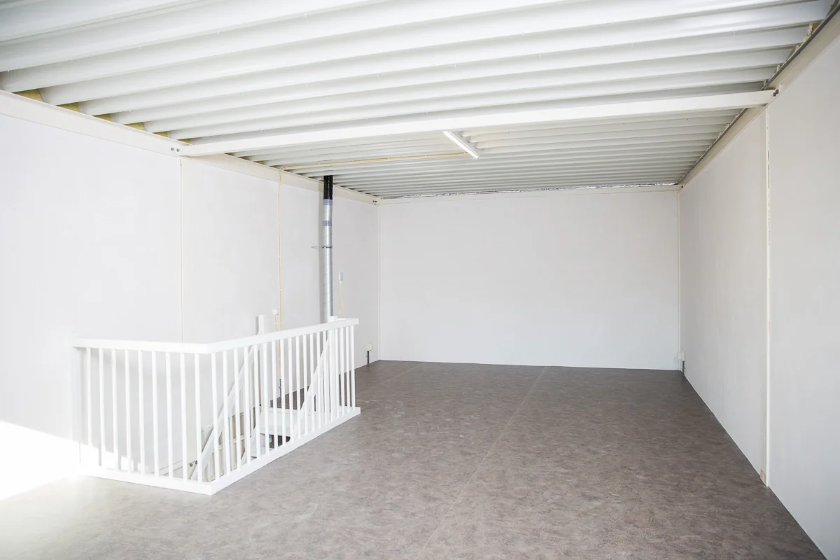 Lege, witte ruimte met metalen plafond, trap met witte balustrade en pvc-vloer aan de Laan van ’s-Gravenmade.