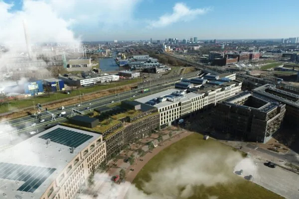 Luchtopname van Reykjavikstraat in Den Haag met moderne gebouwen, snelweg en treinspoor op de achtergrond.