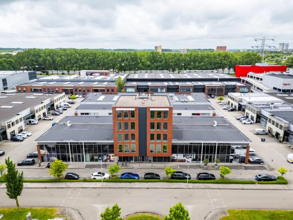 Bedrijfsgebouw aan de Cornusbaan met omliggende parkeerplaatsen en andere bedrijfspanden, gezien vanuit de lucht.