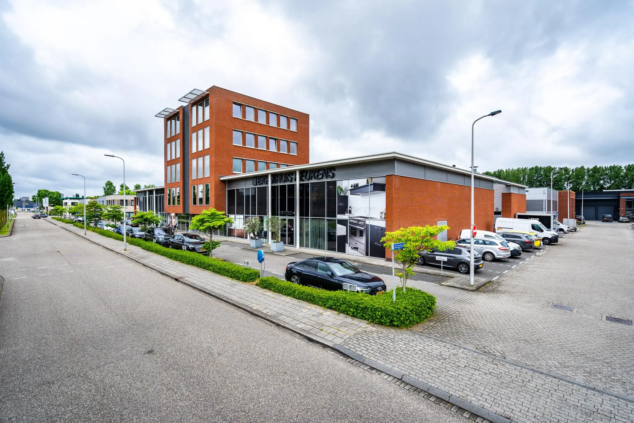 Zakelijk bedrijfsgebouw op de Cornusbaan met showroom van EIGEN HUIS Keukens en parkeerplaatsen ervoor.