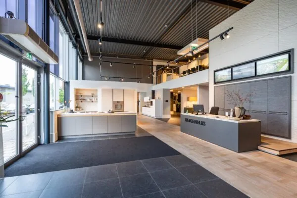 Moderne showroom van Eigenhuis met een stijlvolle receptiebalie, open keukenopstelling en vergaderruimte op de bovenverdieping.