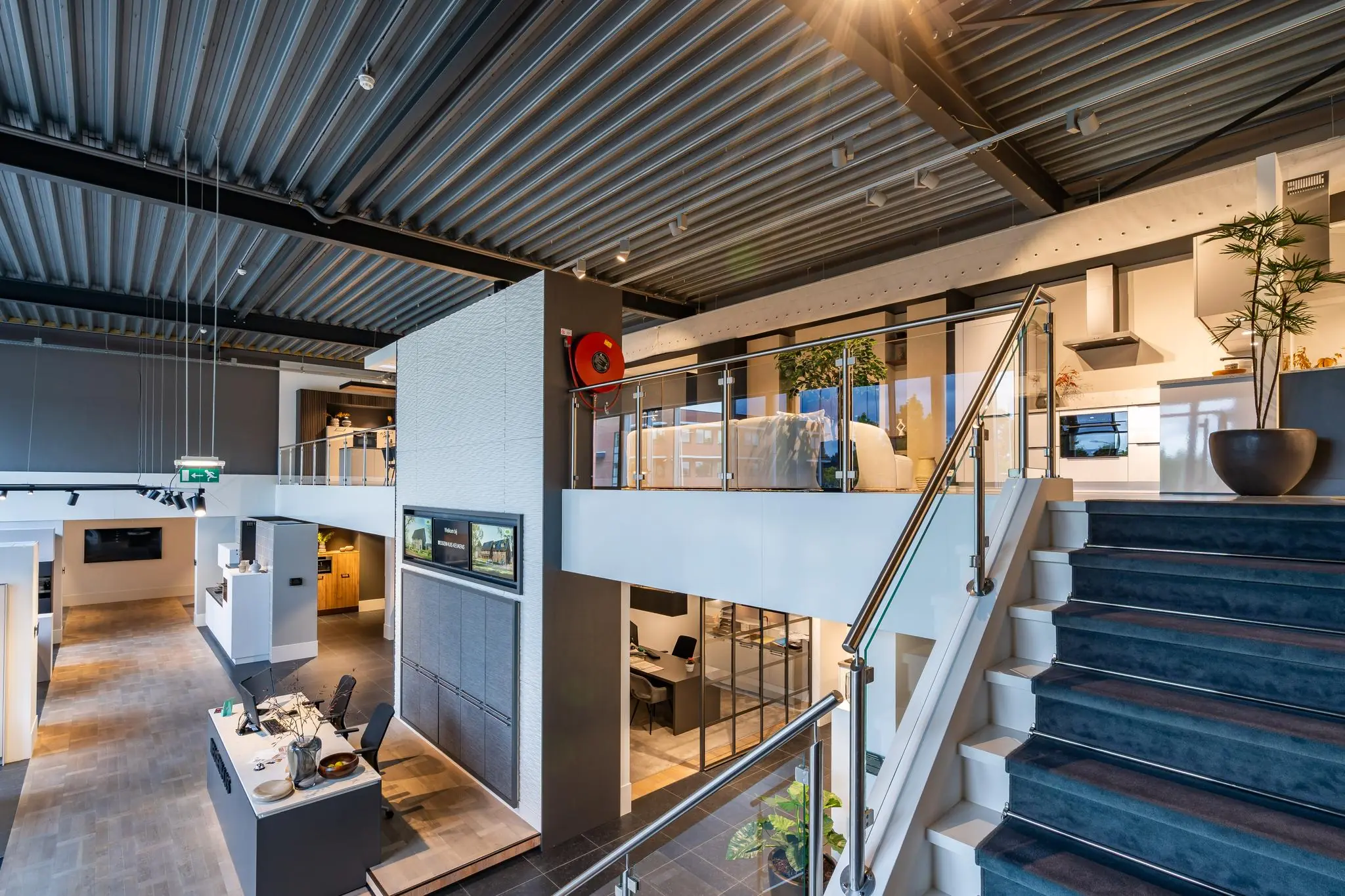 Moderne showroom op de Cornusbaan met een open trap, glazen balustrade en stijlvolle keukenopstellingen.