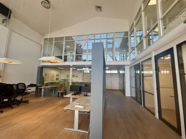 Modern kantoorpand aan het Gedempt Hamerkanaal met glazen wanden, houten vloer en werkplekken.