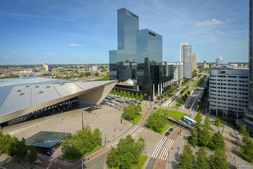 View of Rotterdam Central Station and surrounding modern high-rise buildings along Weena street on a sunny day.