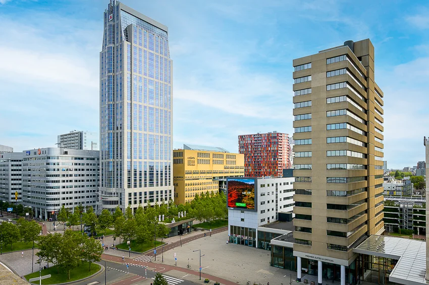Cityscape view of Weena in Rotterdam featuring modern high-rise office buildings and tree-lined streets.