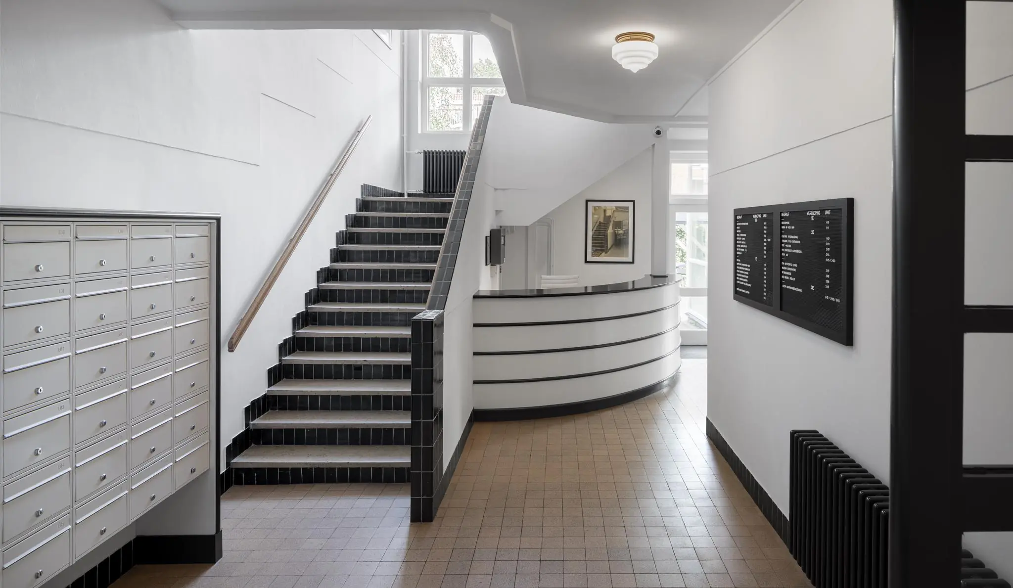Ingangshal van een appartementencomplex aan de Hillegomstraat met brievenbussen, trap, informatiebord en Art Deco details.