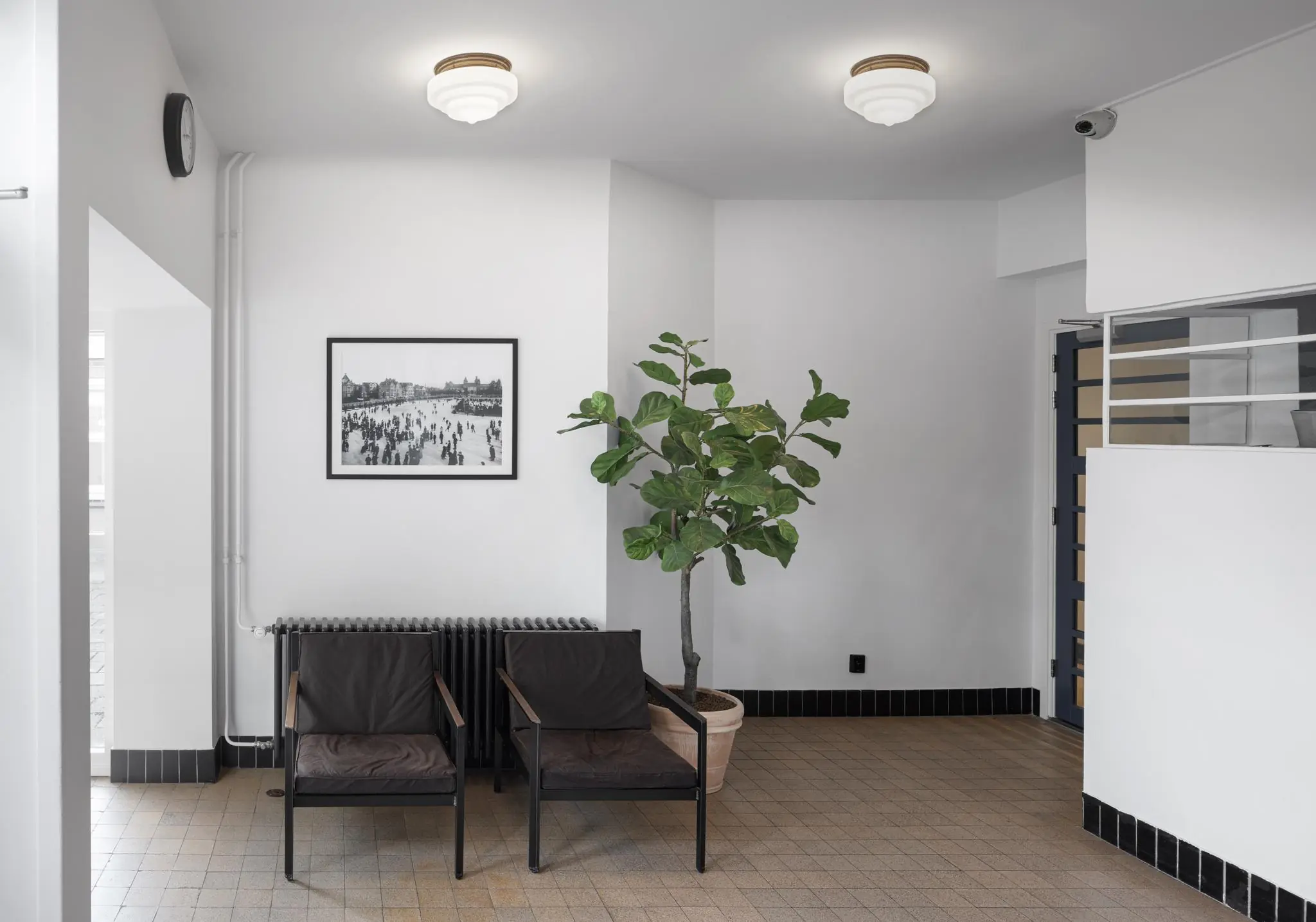 Wachtkamer met twee stoelen, een grote kamerplant, een zwart-witfoto aan de muur en een jaren 30-interieur in de Hillegomstraat.