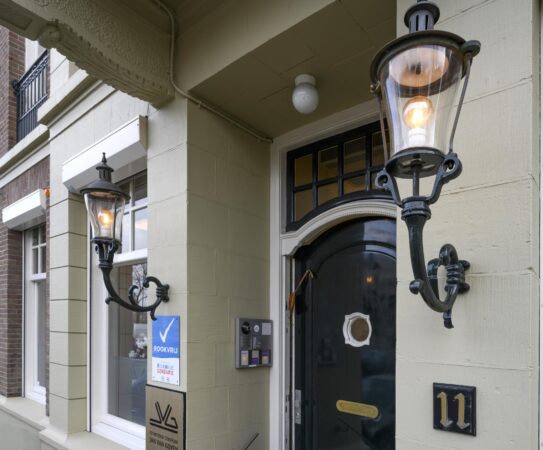 Ingang van een pand aan het Concertgebouwplein met huisnummer 11, voorzien van klassieke wandlantaarns en een bordje van het Jan van Goyen Centrum.