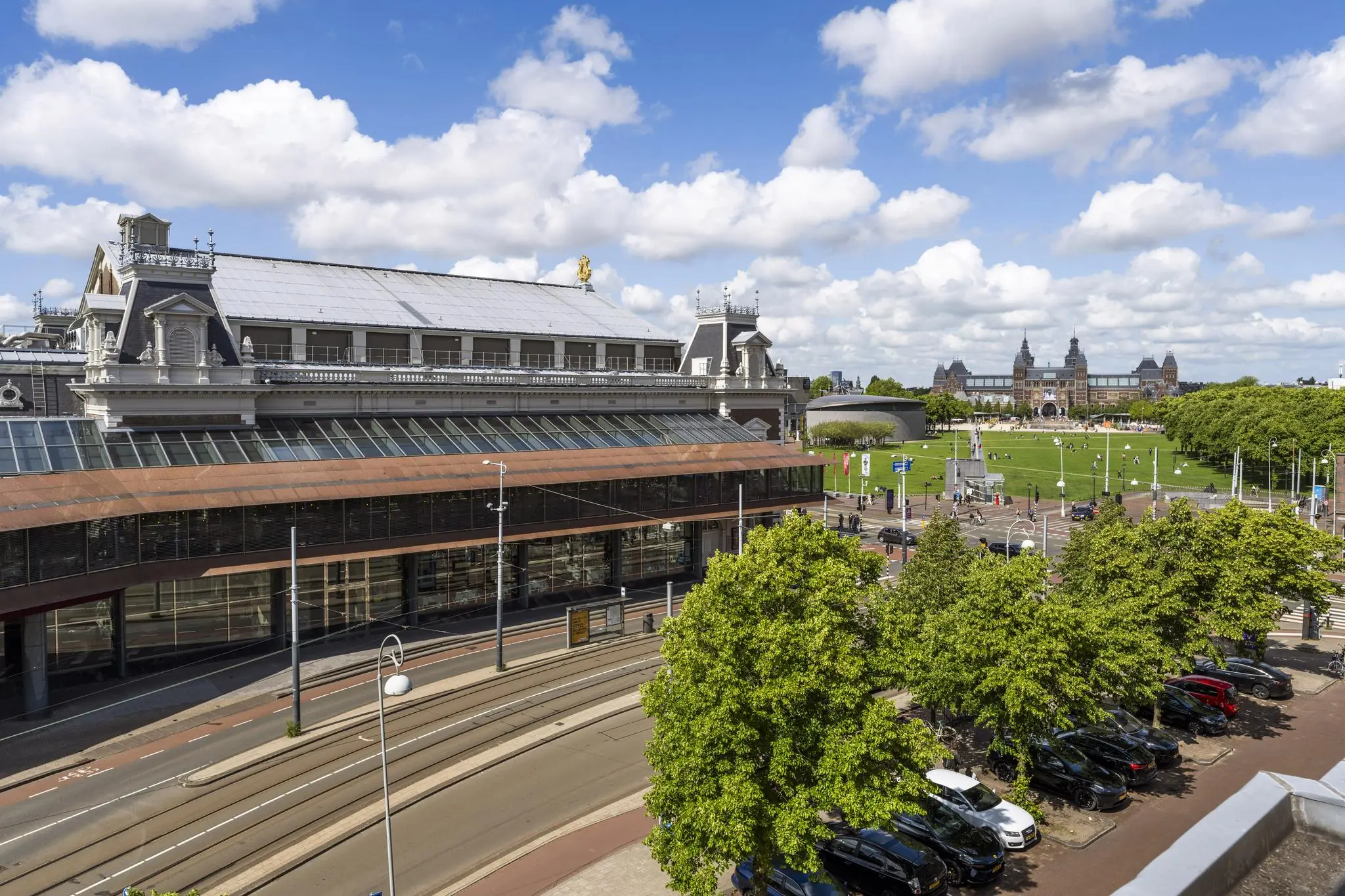 Gezicht op het Concertgebouwplein in Amsterdam met het Concertgebouw op de voorgrond en het Rijksmuseum op de achtergrond.