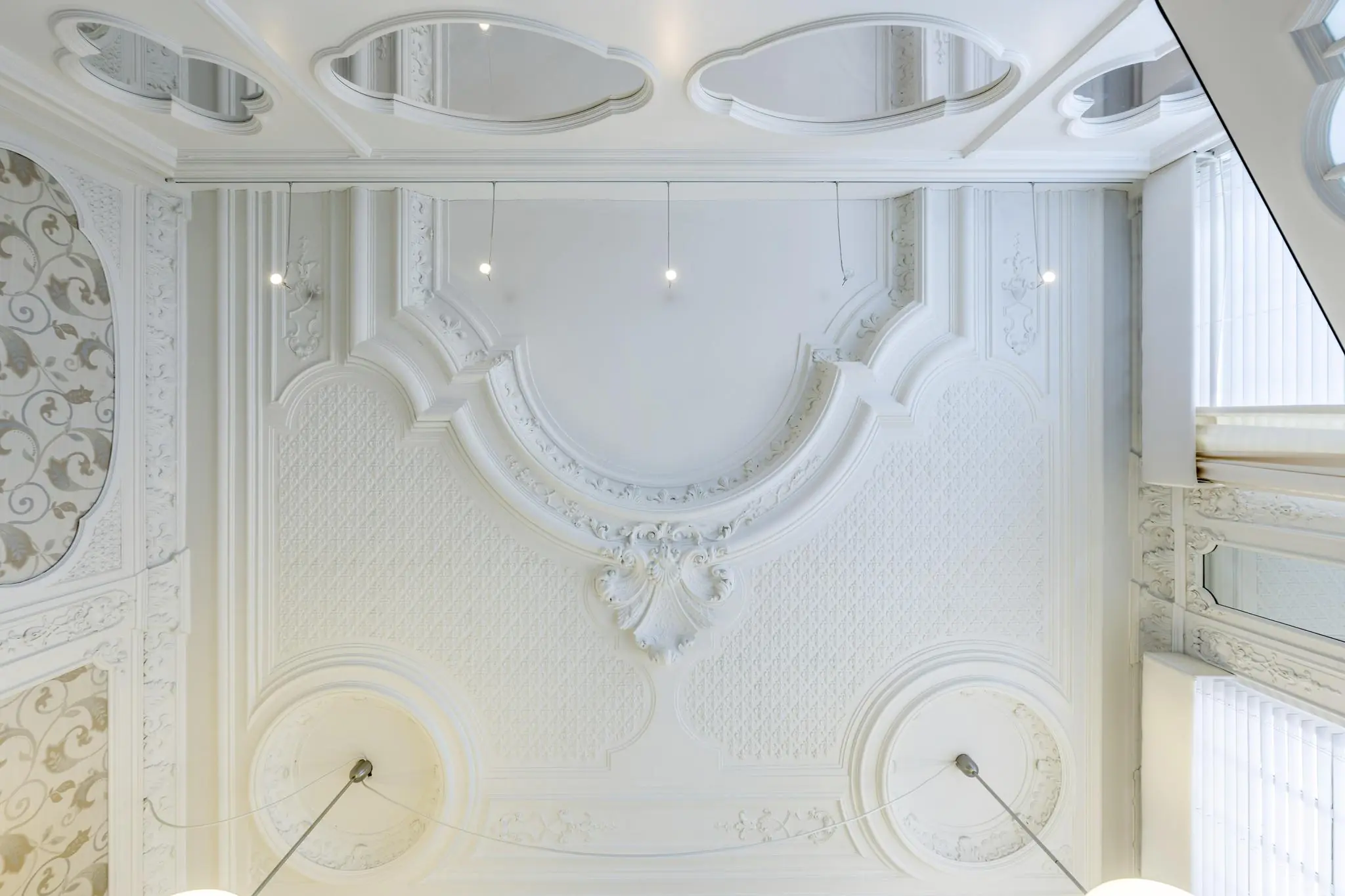 Plafond met sierlijke witte ornamenten en klassieke reliëfdetails in een gebouw aan het Concertgebouwplein.