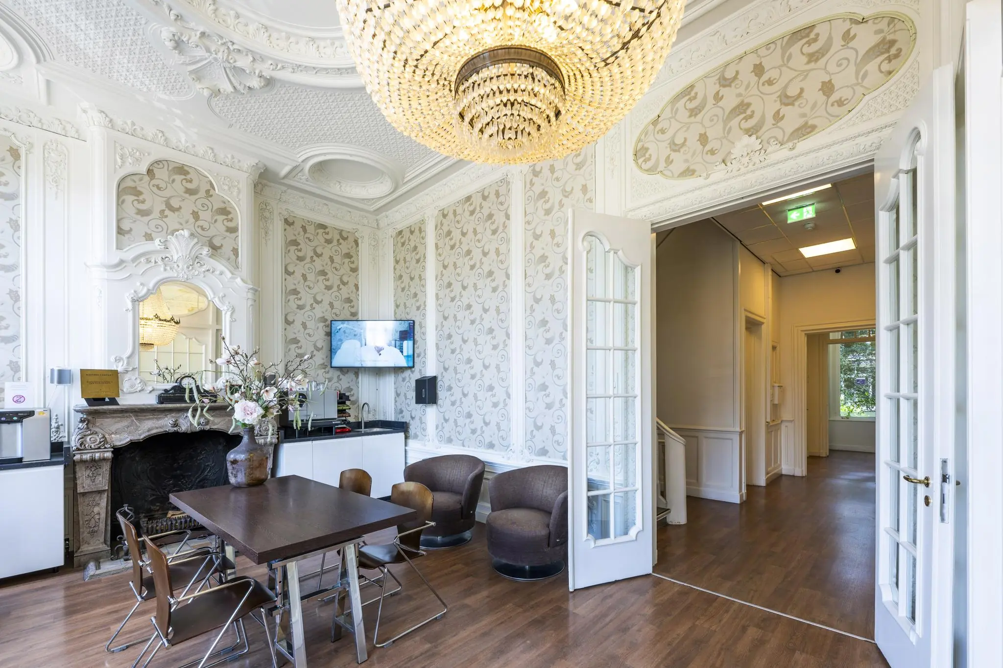 Stijlvolle ontvangstruimte in een historisch gebouw aan het Concertgebouwplein met sierplafond, kroonluchter en moderne zithoek.