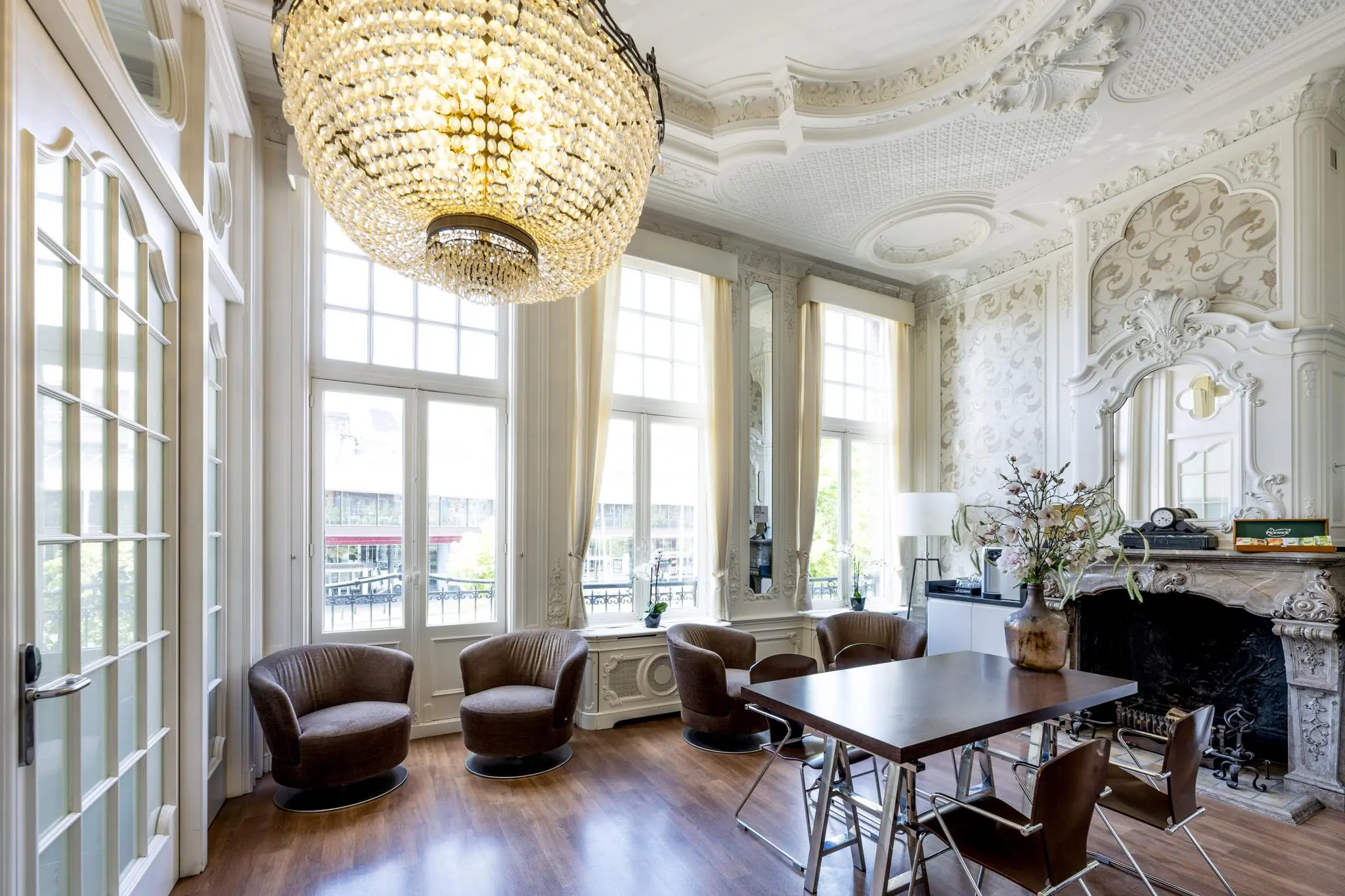 Elegant ingerichte kamer met hoge ramen, sierplafond, kroonluchter en klassieke open haard aan het Concertgebouwplein.