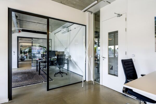 Moderne kantoorruimte aan de Johan van Hasseltweg met glazen wanden, bureaus en ergonomische stoelen.