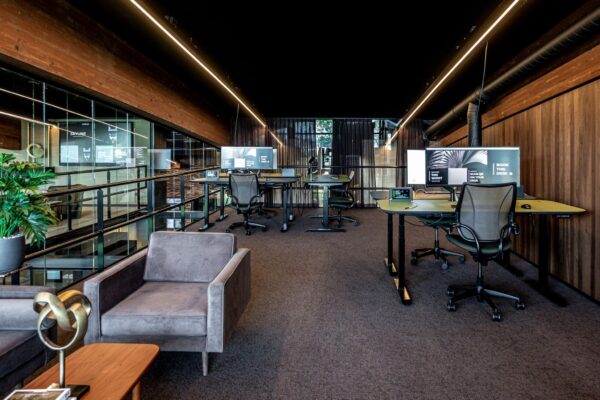 Moderne open kantoorruimte met verstelbare bureaus, ergonomische bureaustoelen en grote monitoren in een stijlvol interieur aan de Plaatweg.