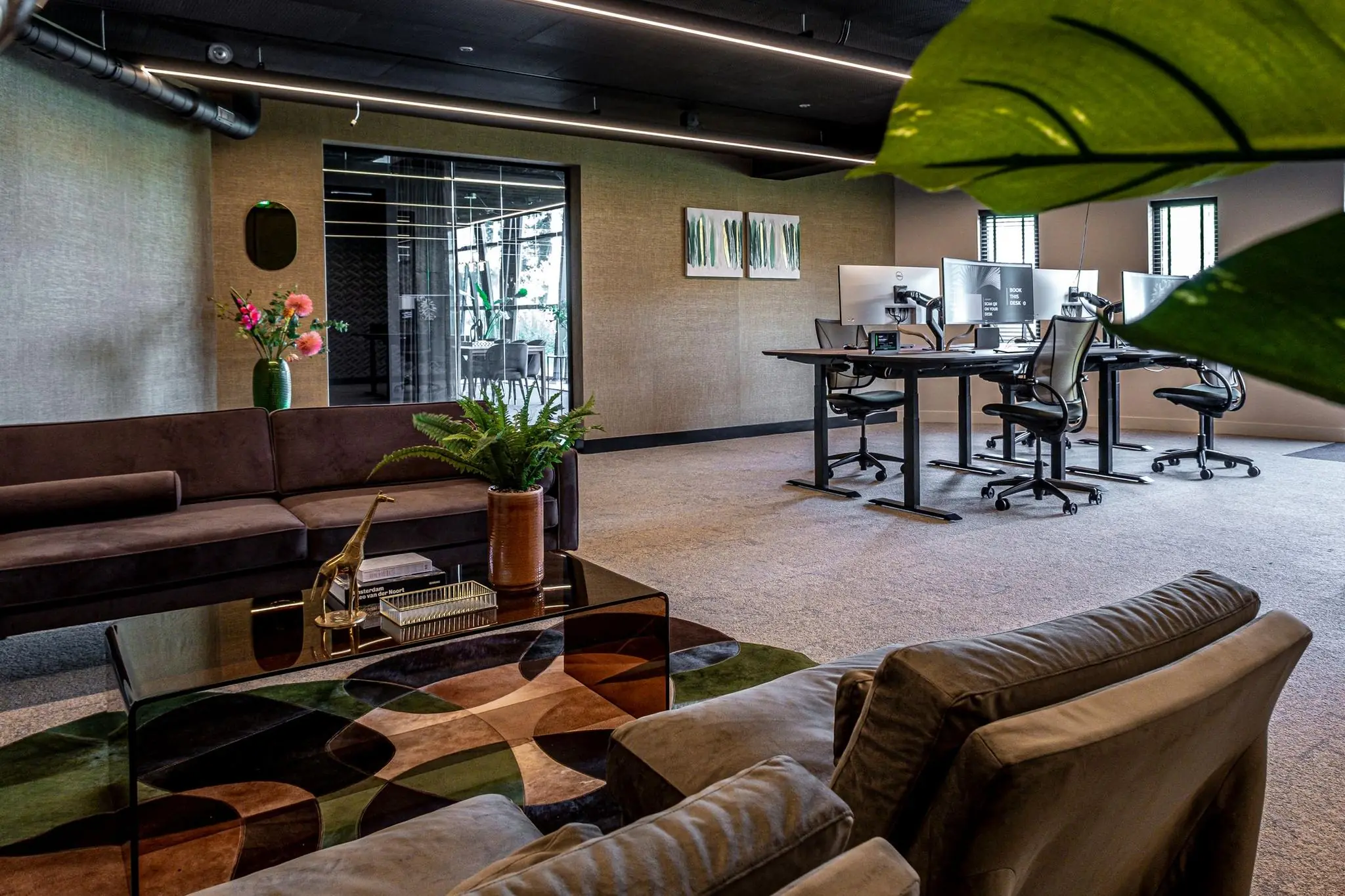 Modern kantoorinterieur aan de Plaatweg met een loungegedeelte, bureaus met dubbele schermen en groene accenten.