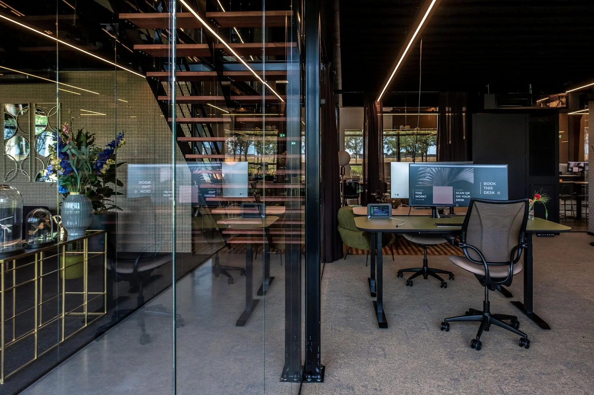 Moderne kantoorruimte aan de Plaatweg met glazen wanden, werkplekken en een open houten trap.