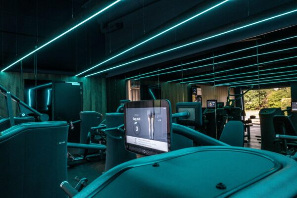 Moderne fitnessruimte aan de Plaatweg met hightech krachttoestellen en sfeervolle blauwgroene LED-verlichting.