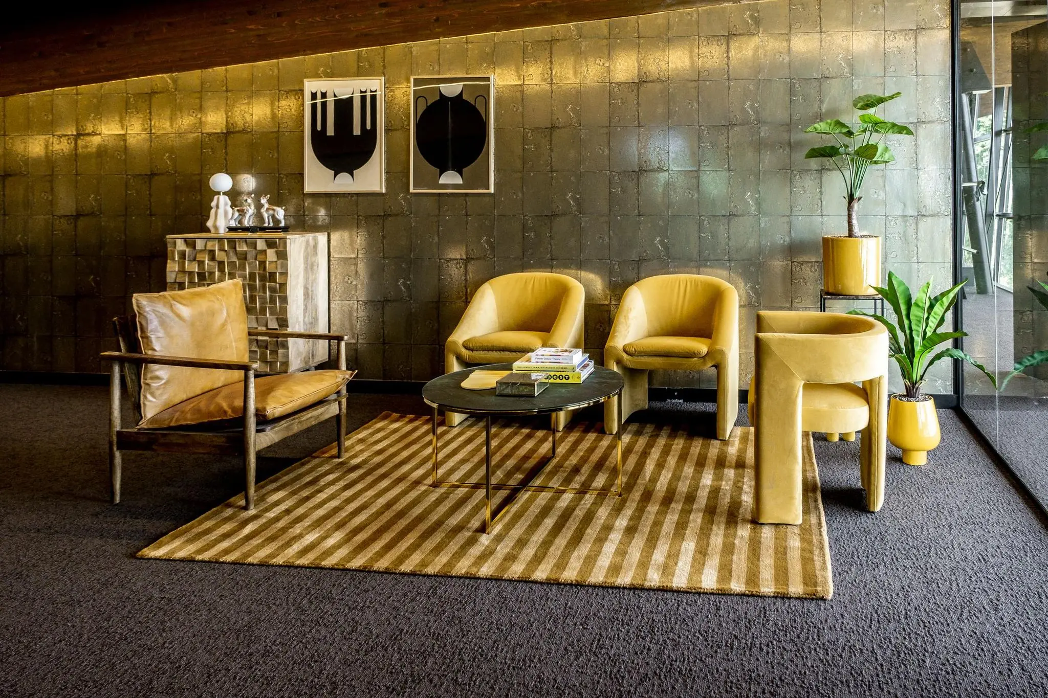 Stijlvolle wachtruimte met gele designstoelen, een ronde salontafel en kamerplanten op een gestreept vloerkleed.