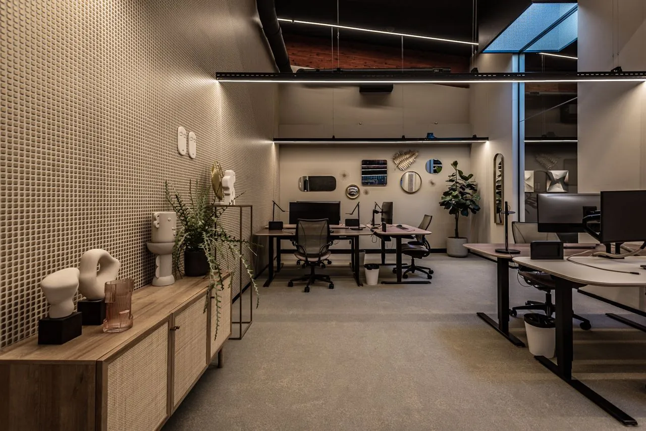 Modern ingericht kantoor met meerdere werkplekken, kunstobjecten en decoratieve spiegels aan de wand.