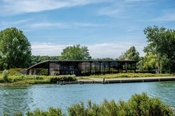 Modern gebouw aan de Plaatweg met glazen gevel, omringd door groen en gelegen aan het water.