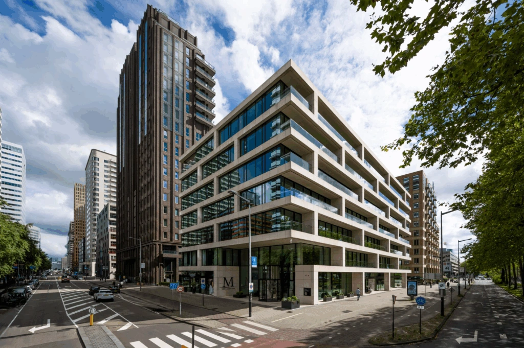 Modern hoekgebouw aan de Gustav Mahlerlaan in Amsterdam met glazen gevels en omliggende hoogbouw.