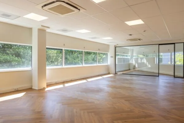 Lichte, lege kantoorruimte aan de Overschiestraat met houten visgraatvloer en glazen scheidingswand.