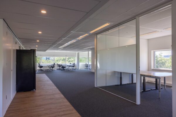 Modern kantoorinterieur aan de Overschiestraat met glazen vergaderruimte en werkplekken bij het raam.