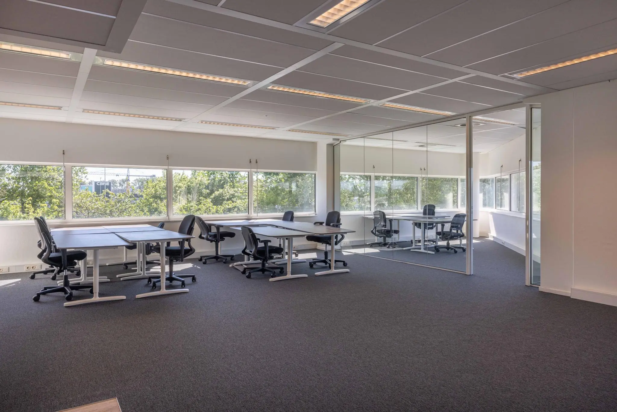 Licht en modern kantoorinterieur aan de Overschiestraat met bureaus, stoelen en grote ramen met uitzicht op groen.