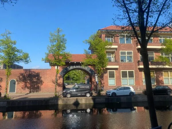 Gebouw met een poort met de tekst "De Zuster" aan de Gasthuisplaats, gezien vanaf de overkant van een gracht.